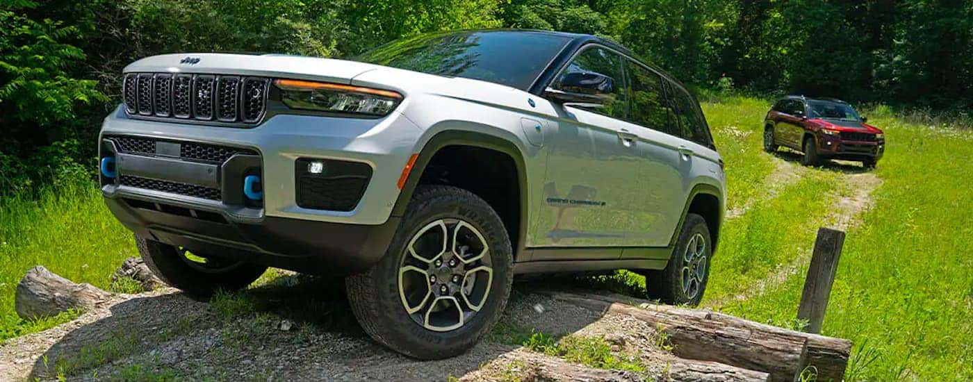 A maroon 2022 Jeep Grand Cherokee and Grand Cherokee 4xe are shown off-roading.