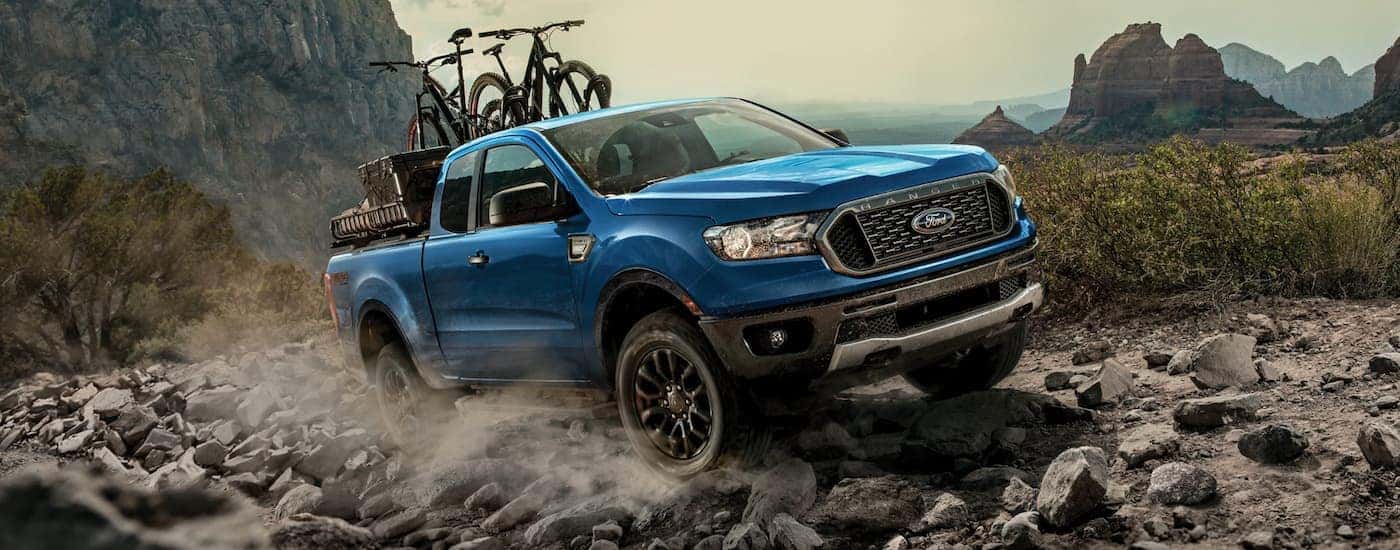 A blue 2021 Ford Ranger FX4 is shown off-roading with bikes in the bed.