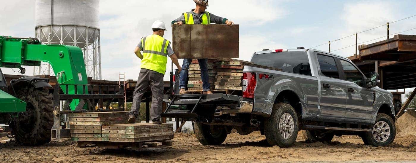 Construction workers are shown loading the bed of a grey 2022 Ford F-250 Super Duty FX4.