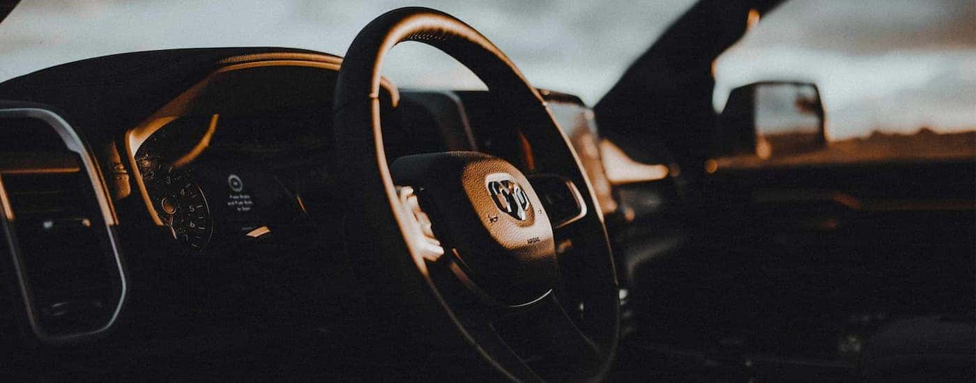 A close up shows the steering wheel and dash in a 2022 Ram 1500 at dusk.