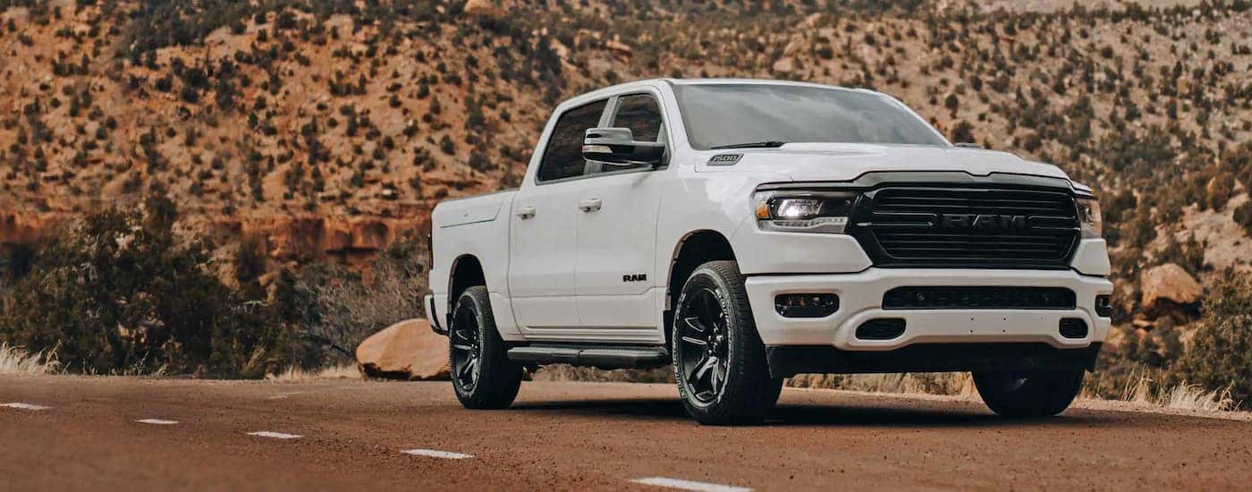 A white 2022 Ram 1500 is shown parked on a dusty road.
