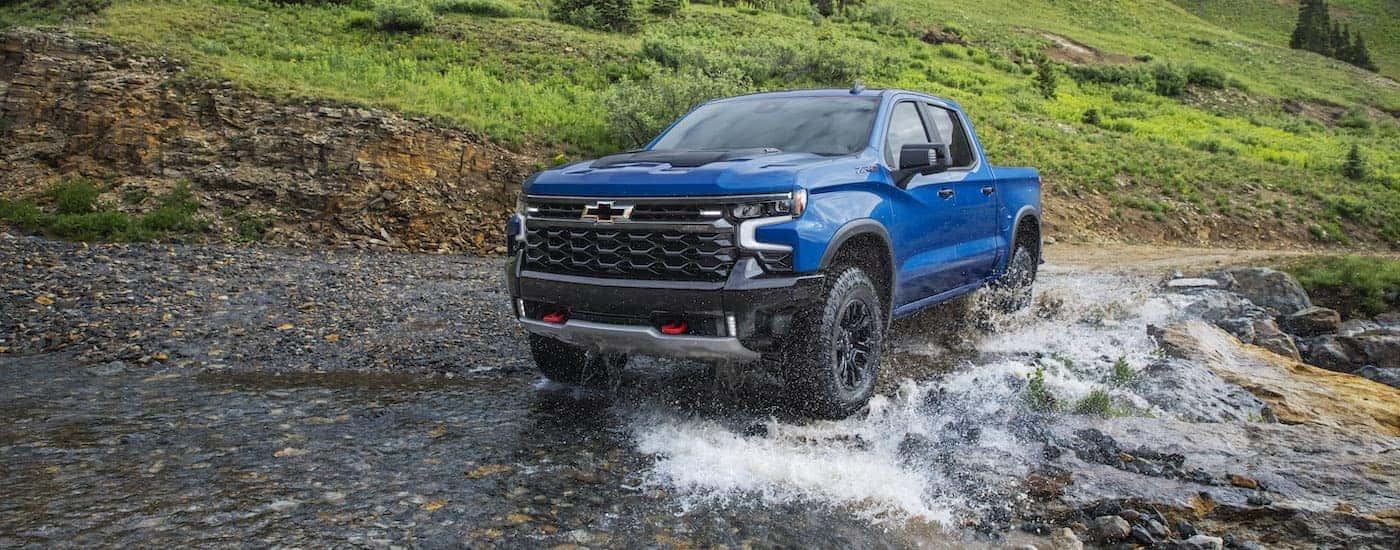 A blue 2022 Chevy Silverado 1500 ZR2 is shown driving through a creek.