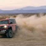 A red 2022 Ford Bronco Raptor is shown from the front while it drifts through the desert after leaving a Crested Butte Ford dealer.