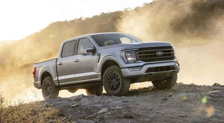 A silver 2022 Ford F-150 Tremor is shown from the front at an angle while parked in a rocky area after leaving an Alamosa Ford dealership.