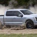 A silver 2022 Ford F-150 Lightning Lariat is shown from the side on a dirt course after leaving a Gunnison Ford dealer.
