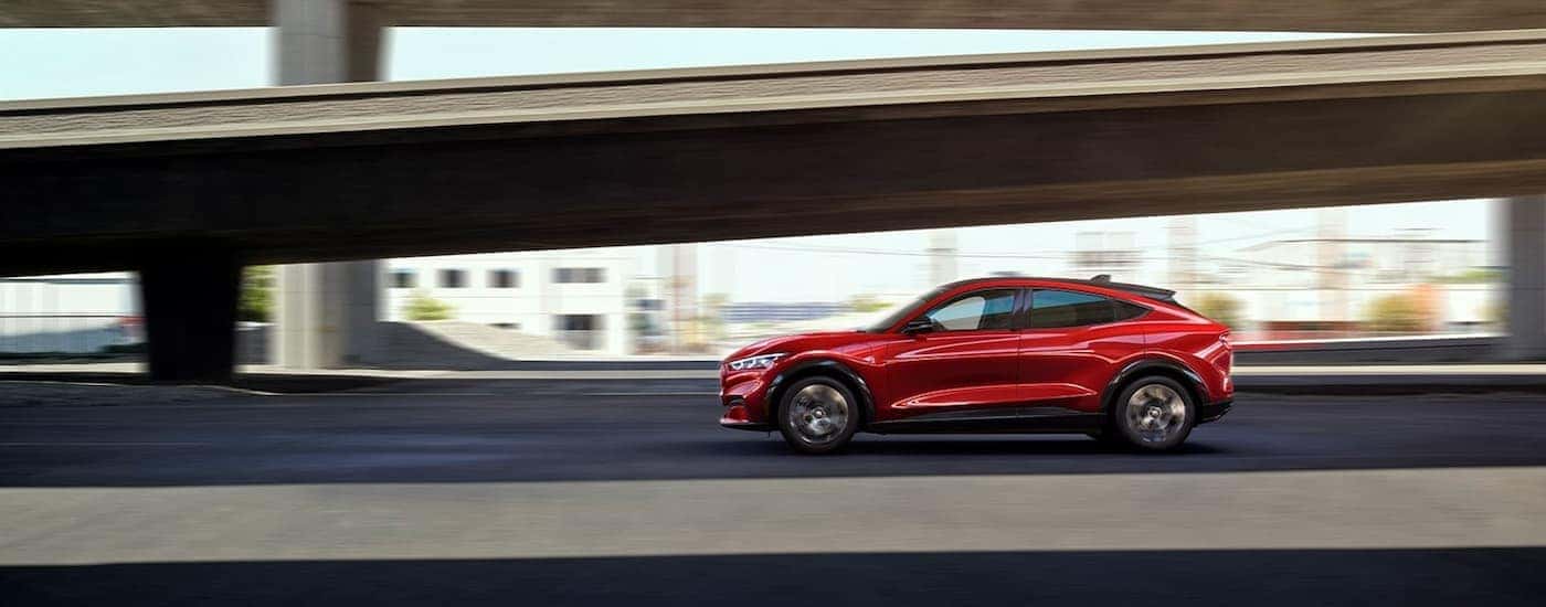 A red 2022 Ford Mustang Mach-E is shown from the side leaving a Fremont County Ford dealership.