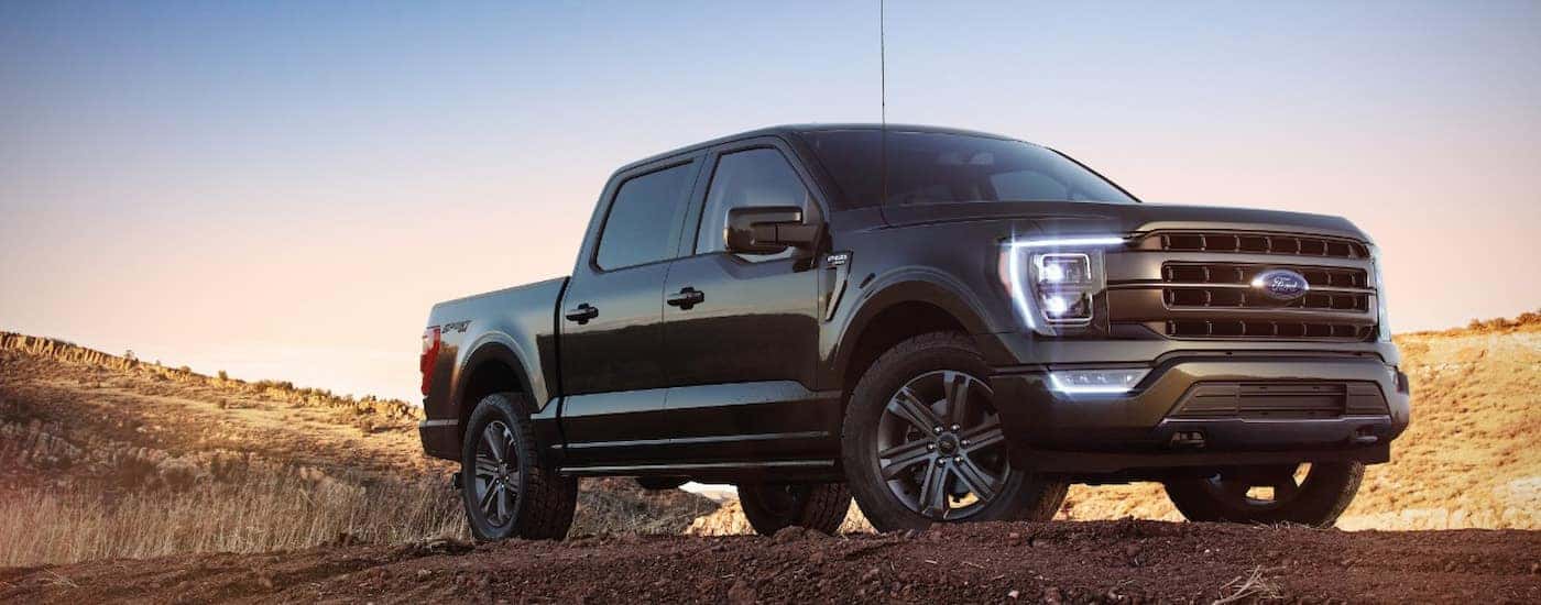 A black 2022 Ford F-150 Lariat is shown parked in an open dirt lot.