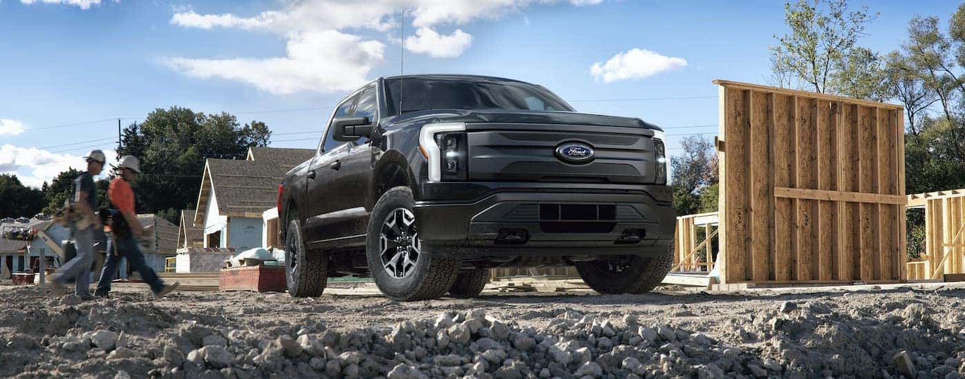 A black 2022 Ford F-150 Lightning Pro is shown parked on a construction site.