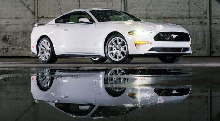 A white 2022 Ford Mustang Ice White Edition is in a warehouse with its reflection shown in a puddle.