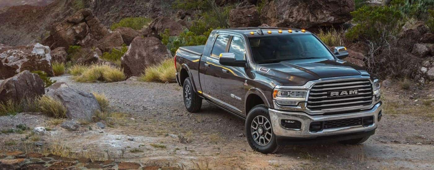 A grey 2021 Ram 1500 Limited Longhorn, a popular used truck for sale, is shown parked on a dirt road.