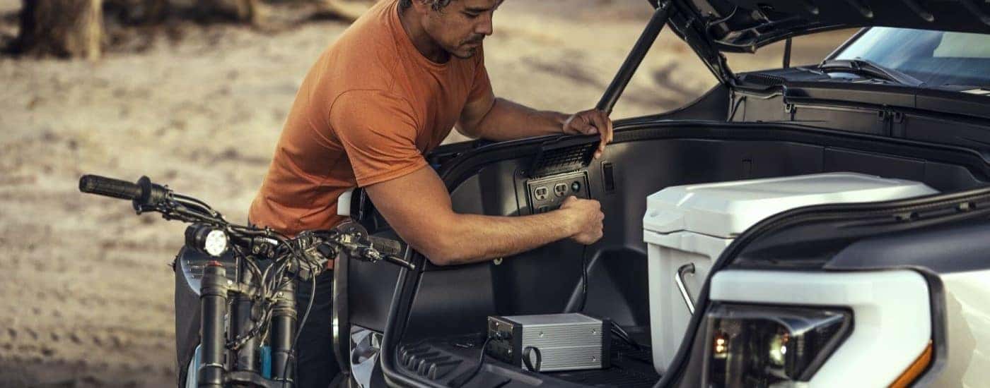 The electric outlet in a silver 2024 Ford F-150 Lightning is shown being utilized.