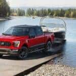 A 2023 Ford F-150 XLT Heritage Edition is shown towing a boat after visiting Faricy Boys Automotive looking for a used Ford F-150 for sale near Poncho Springs, CO.