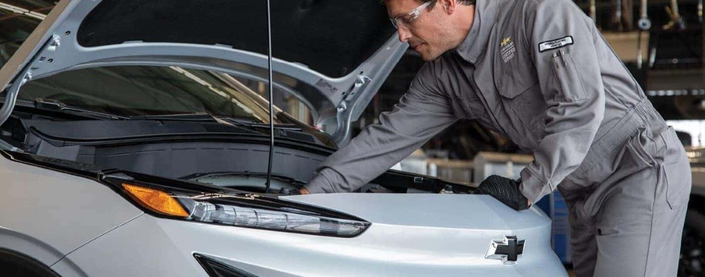 A technician is shown performing an electric car repair on a silver 2023 Chevy Bolt EUV.
