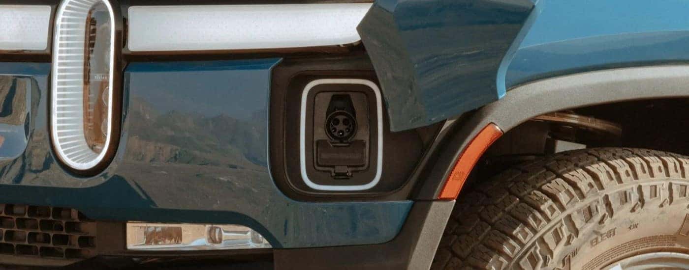 A close up shows the charge port on a blue 2023 Rivian R1T.