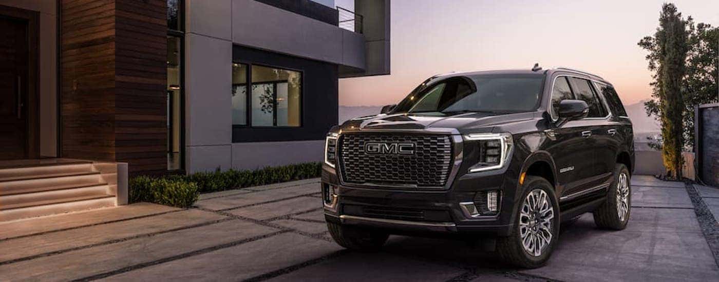 A black 2023 GMC Yukon Denali Ultimate is shown from the front at an angle after leaving a dealer that has SUVs for sale.