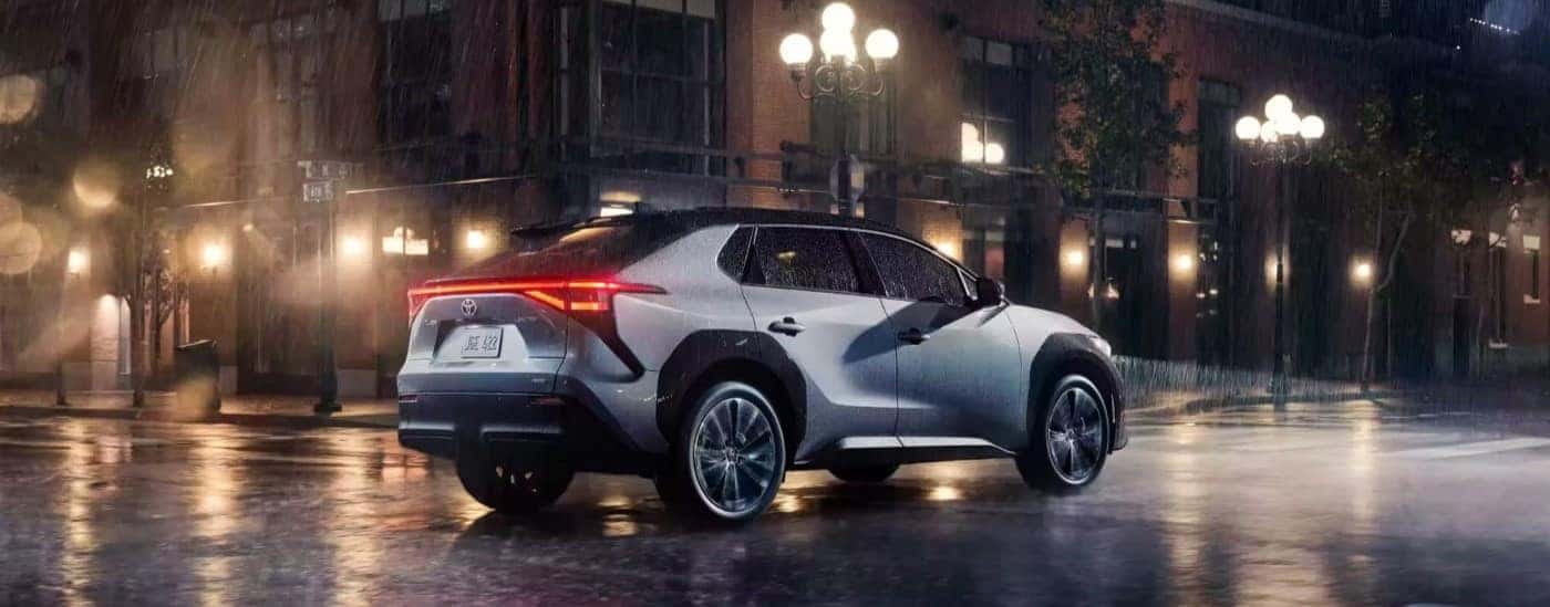 A silver 2023 Toyota bZ4X Limited is shown driving on a rainy night.