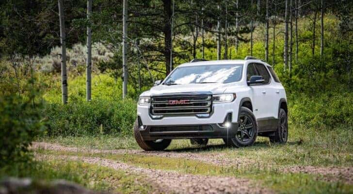 A white 2020 GMC Acadia AT4 is shown from the front at an angle while off-road after leaving a used GMC dealer.