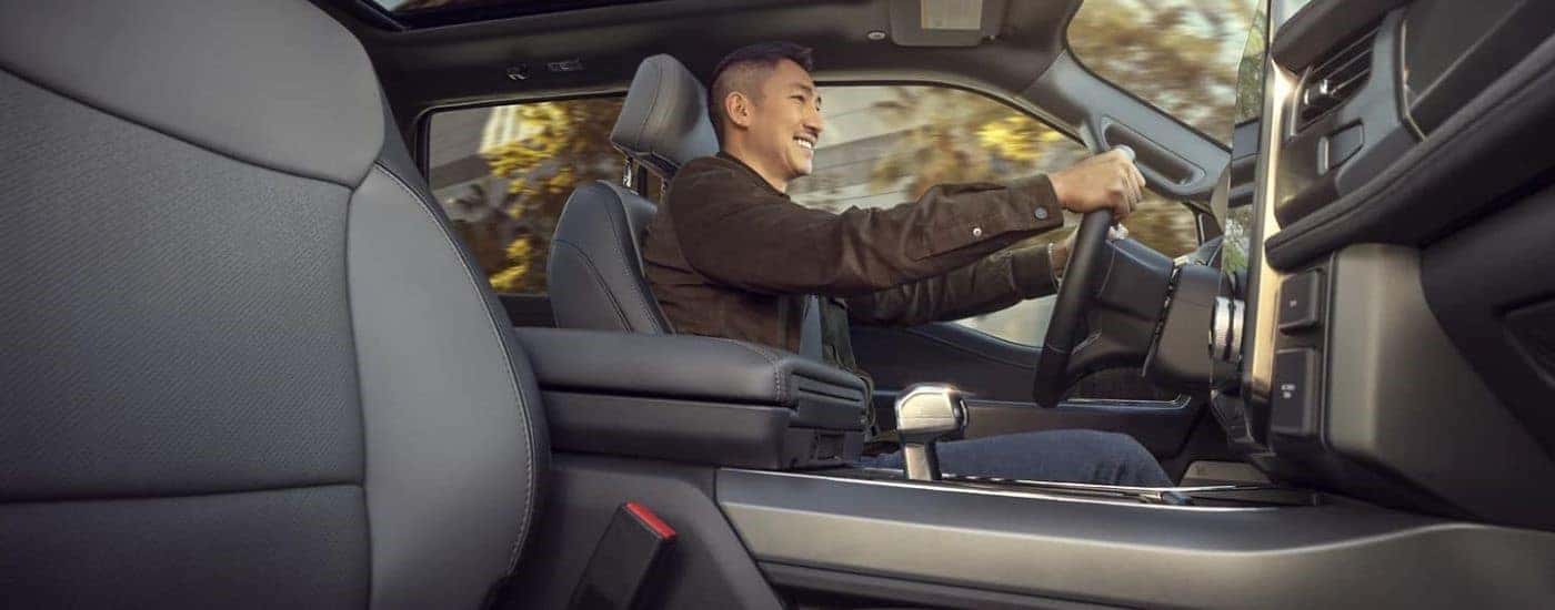 A man is shown driving in a 2023 Ford F-150 Lightning.