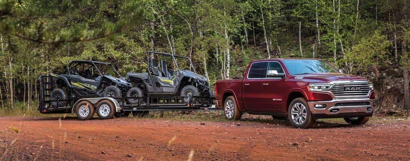 A red 2023 Ram 1500 is shown towing a trailer.