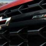 A close-up on the grille and badge of a red 2024 Chevy Silverado 2500 HD ZR2 is shown.