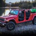 A red 2024 Jeep Gladiator Rubicon is shown parked near a stream.