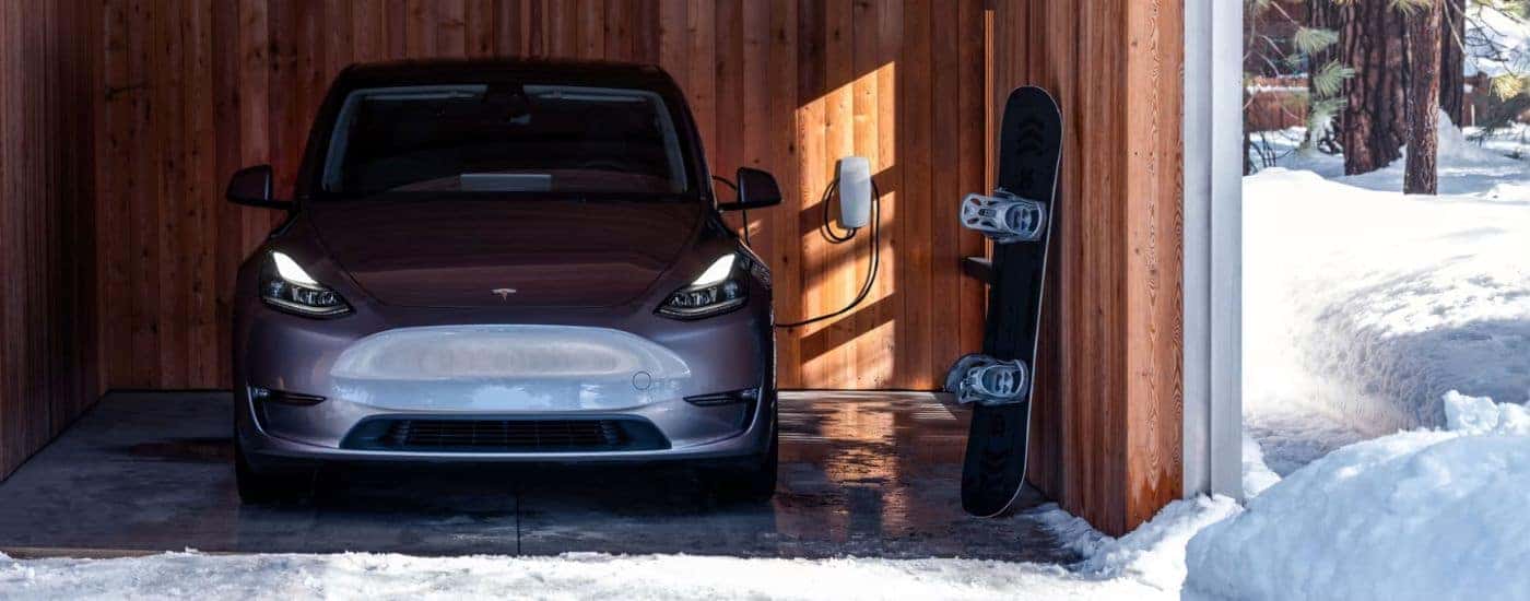 A grey 2021 Tesla Model 3 is shown in a garage with a snowboard.
