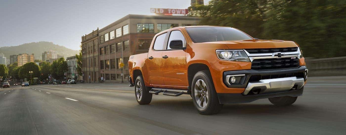 An orange 2021 Chevy Colorado Z71 driving in a city.