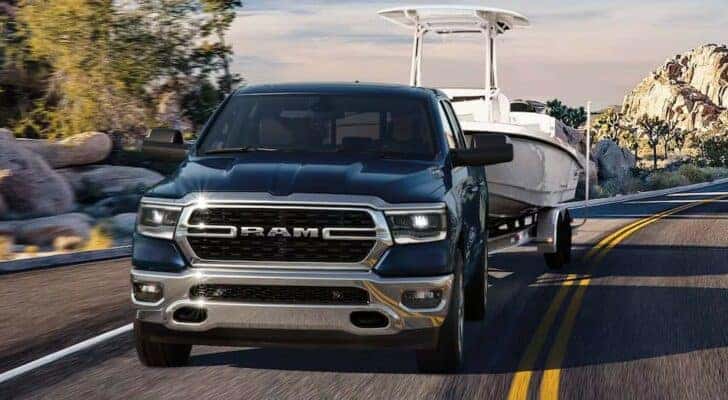 A black 2024 Ram 1500 towing a boat.