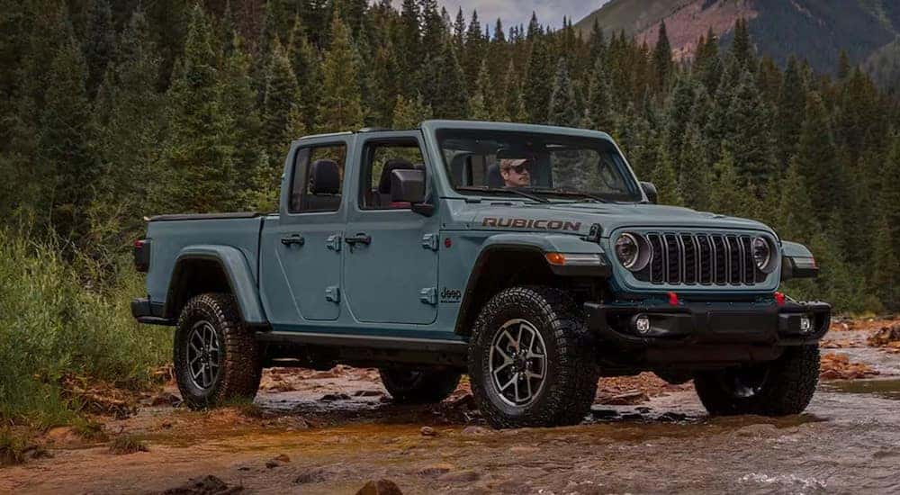 A blue 2025 Jeep Gladiator Rubicon is shown parked near a forest.