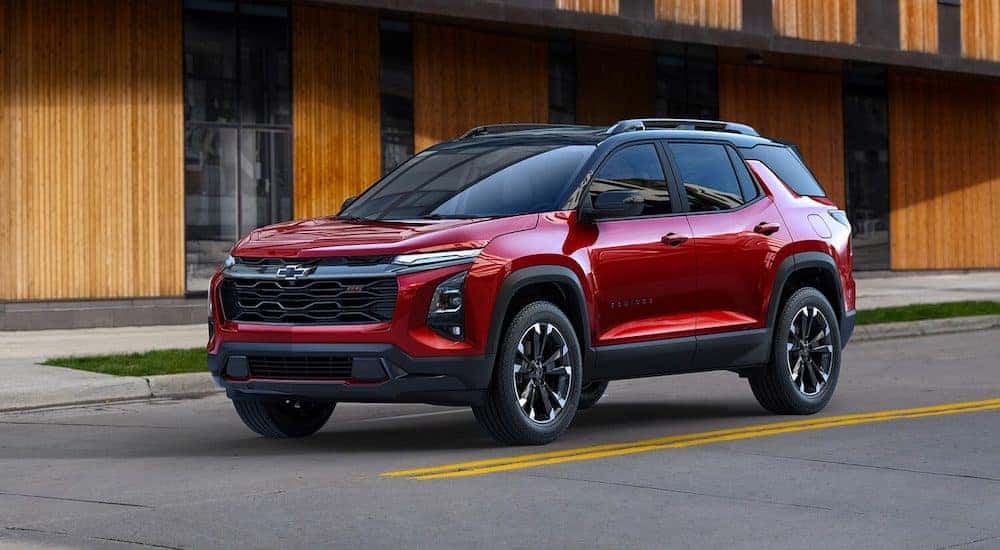 A red 2025 Chevy Equinox driving by a Chevy dealer.