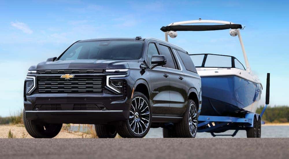 A black 2025 Chevy Suburban High Country towing a boat.