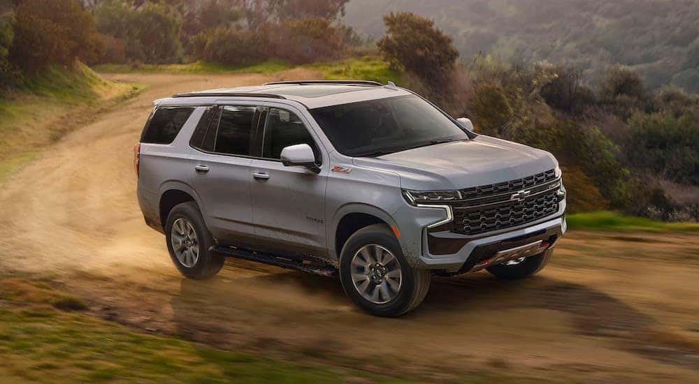A grey 2025 Chevy Tahoe Z71 driving on a dirt road.
