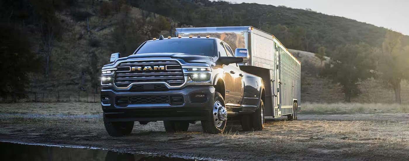 A gray 2025 Ram 3500 is shown towing a trailer off-road.