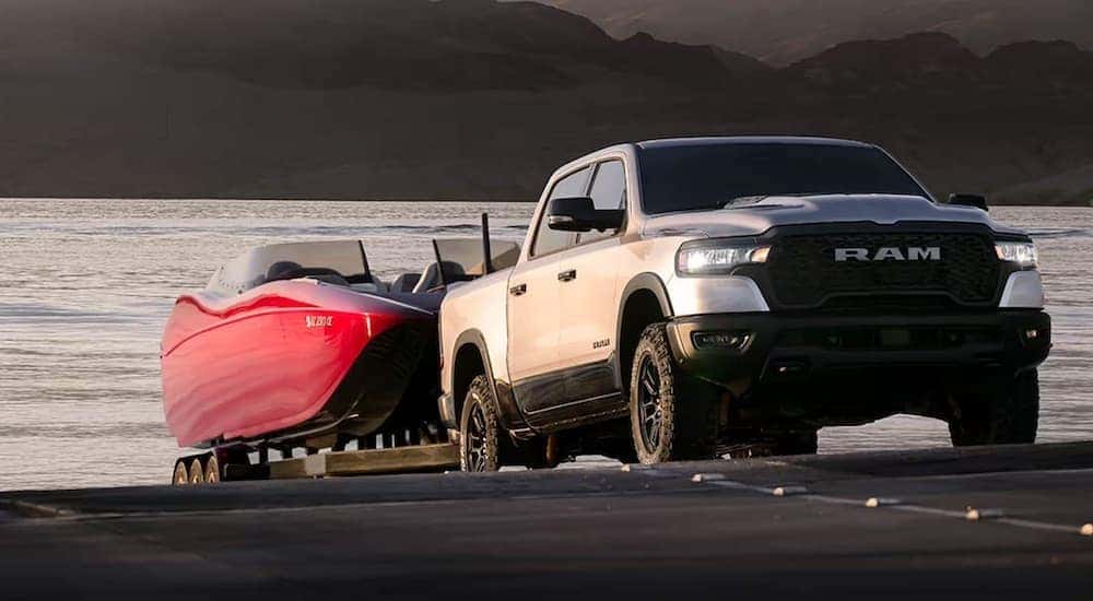 A silver 2025 Ram 1500 is shown from the front at an angle while loading a boat.