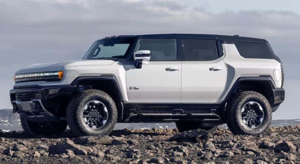 A white 2025 GMC Hummer EV SUV is shown parked off-road.