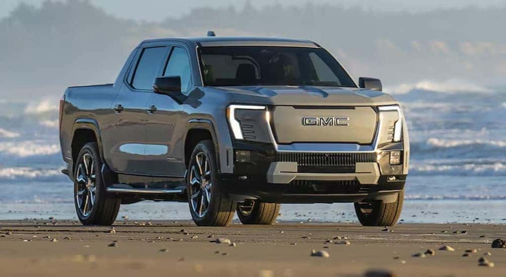 A silver 2025 GMC Sierra EV is shown parked near an ocean.