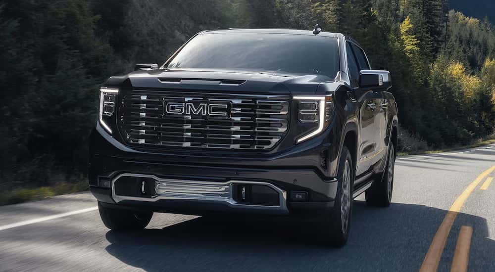 A black 2025 GMC Sierra 1500 Denali Ultimate driving from a GMC dealer.