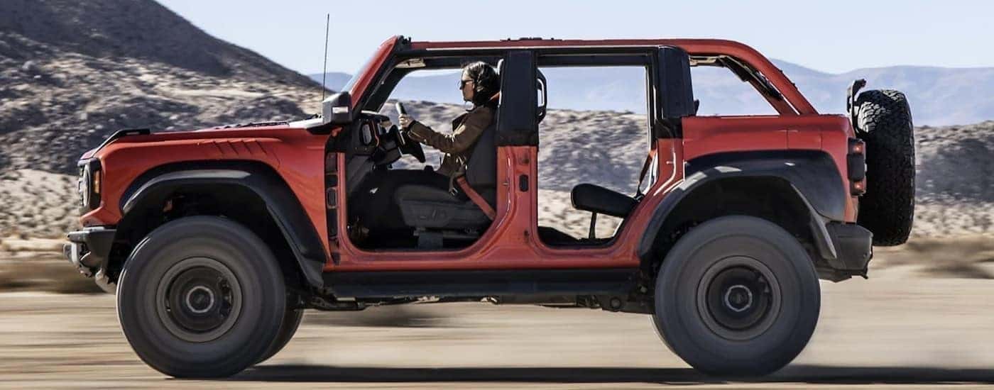 An orange 2025 Ford Bronco Raptor is shown from the side.
