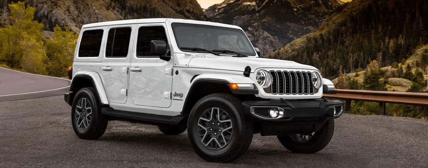 White 2025 Jeep Wrangler Sport parked on the side of road.
