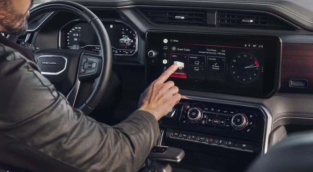 A man using the touch screen infotainment display in a 2024 GMC Sierra 1500 Denali