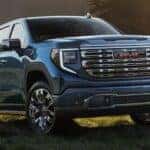 A blue 2025 GMC Sierra 1500 Denali parked on grass
