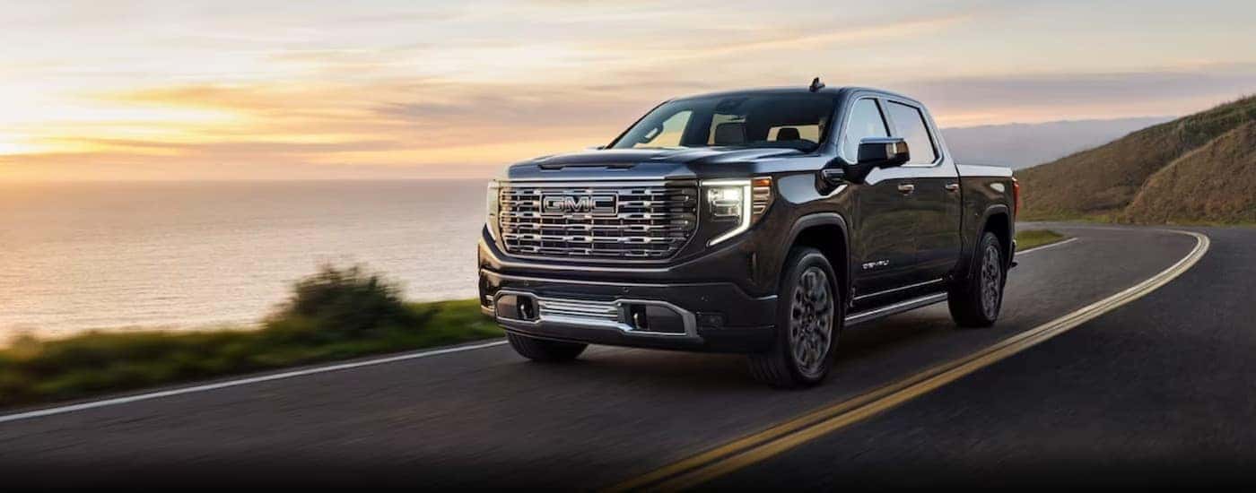 A gray 2024 GMC Sierra 1500 Denali driving on a highway.