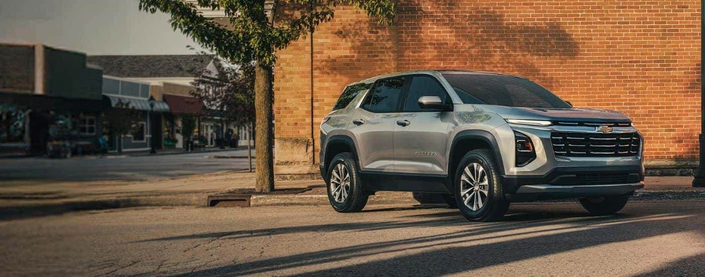 A silver 2025 Chevy Equinox parked in front of a brick building.