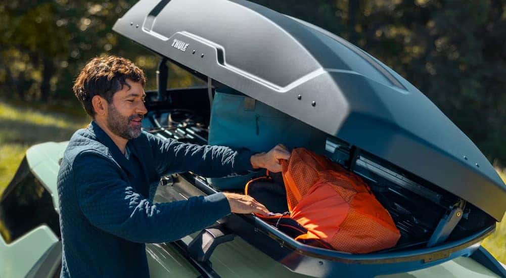 A person utilizing roof storage on a green 2026 Chevy Equinox.