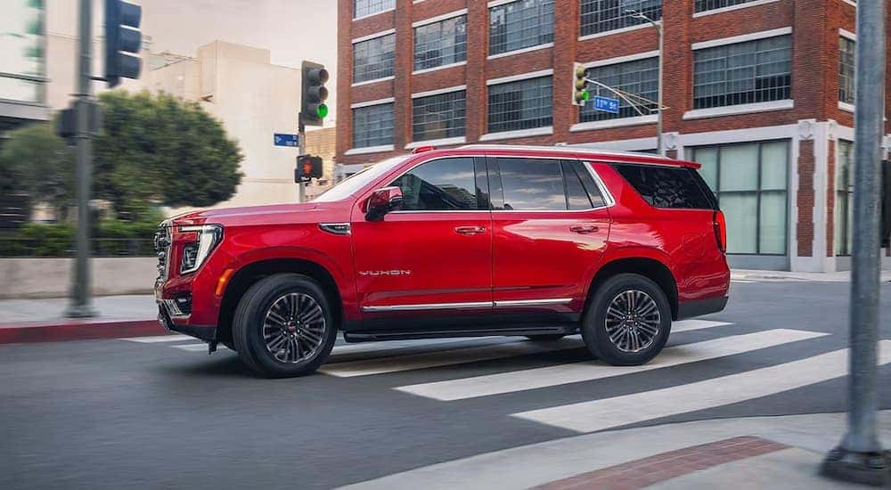 A red GMC Yukon driving in a city