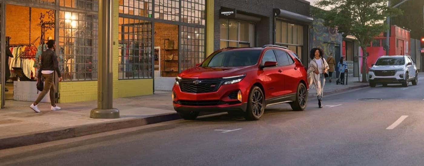 A red 2024 Chevy Equinox parked by a street curb after visiting a Chevy dealer.