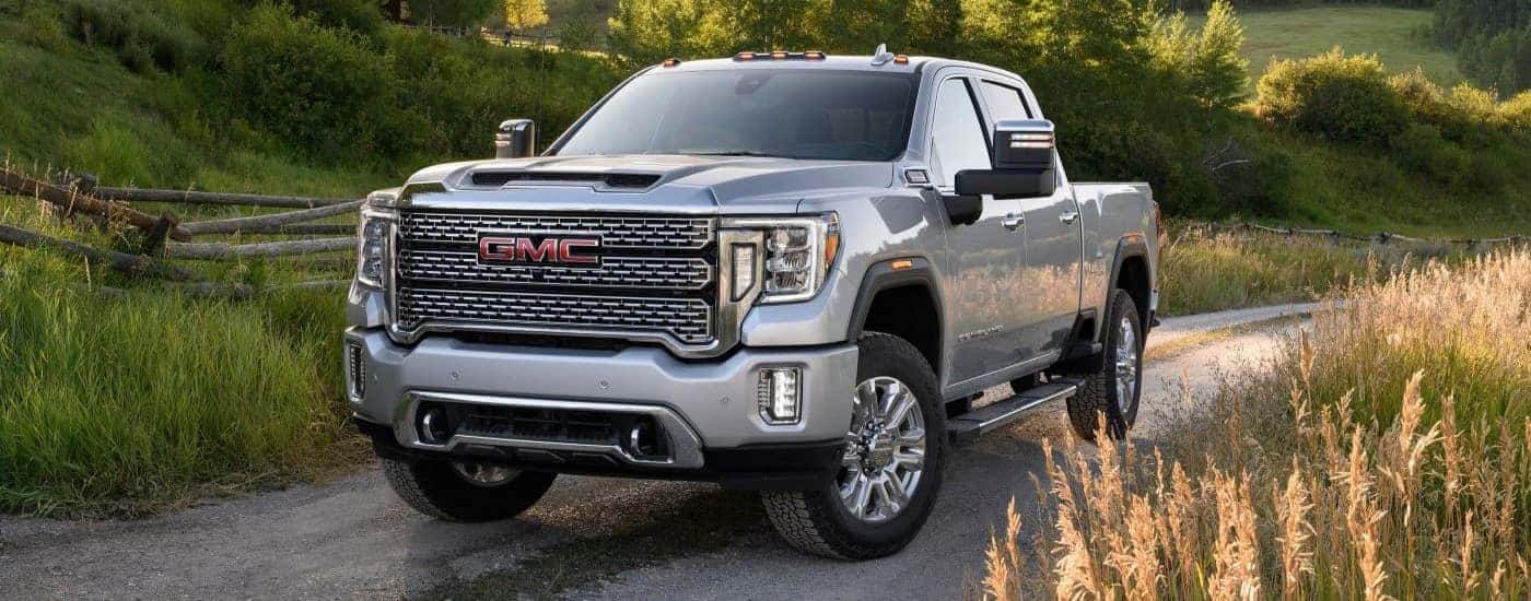 A white 2024 GMC Sierra 2500 HD Denali driving on a dirt road.