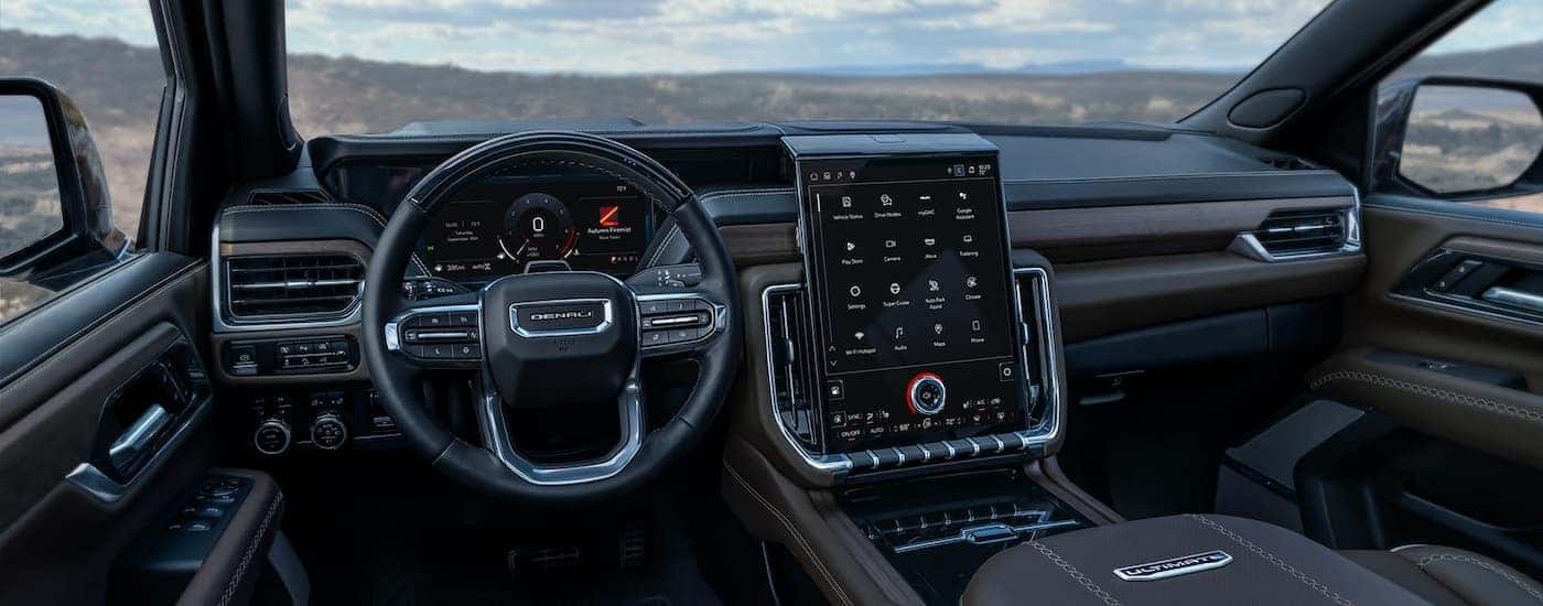 Steering wheel and dashboard interface in the black interior of a 2026 GMC Yukon XL.
