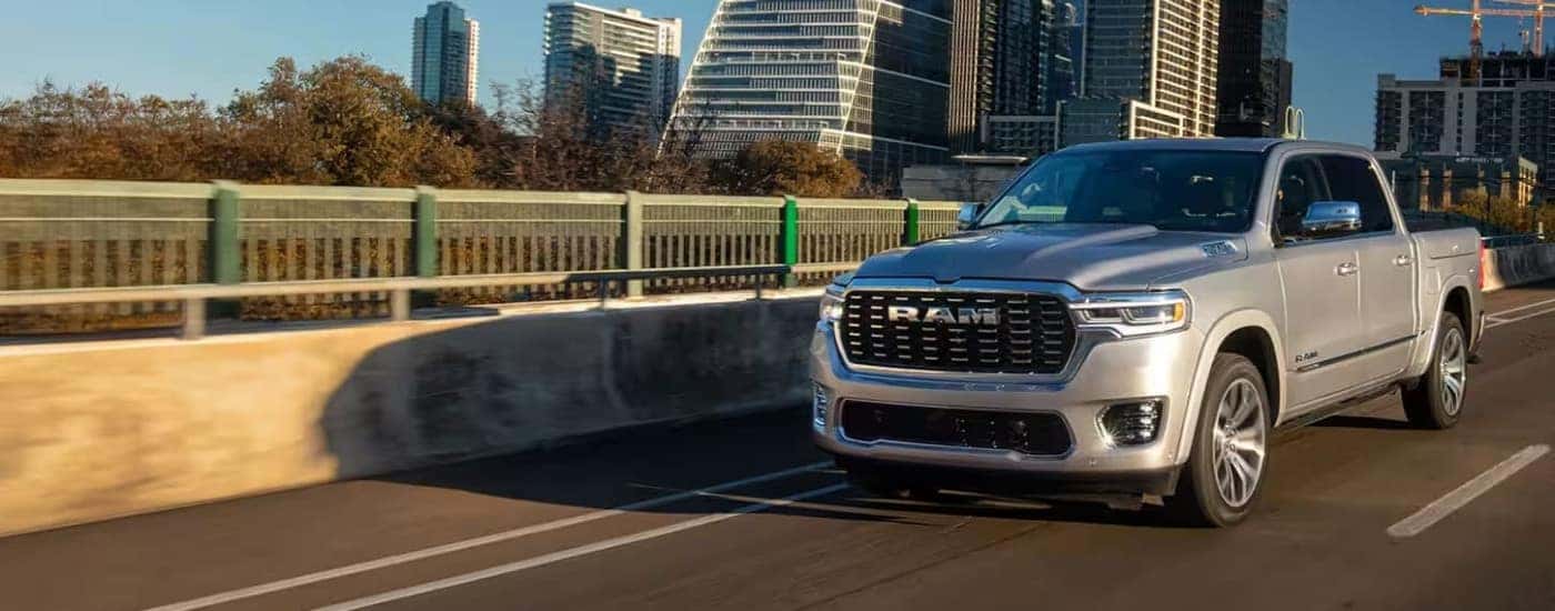 A silver 2025 Ram 1500 is shown driving after visiting a Ram dealer.