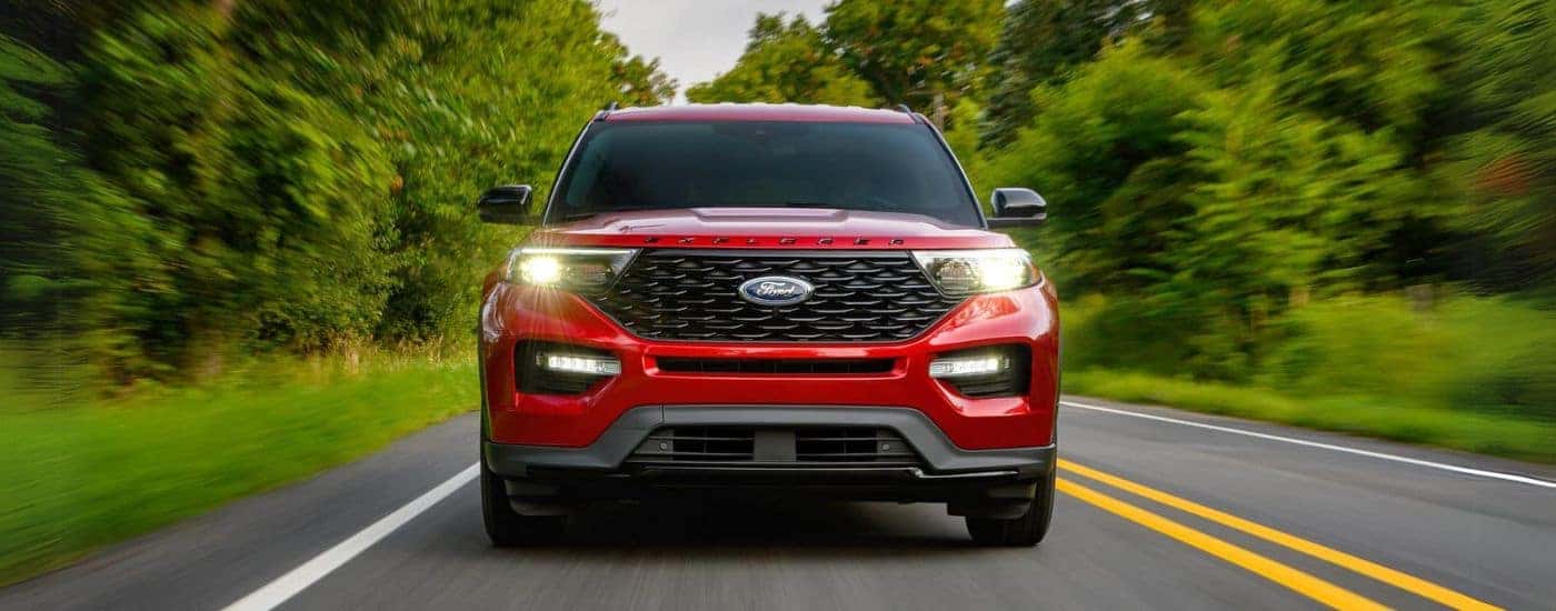 A red 2022 Ford Explorer ST-Line is shown driving down a wooded road after leaving a Colorado Ford Explorer dealer.